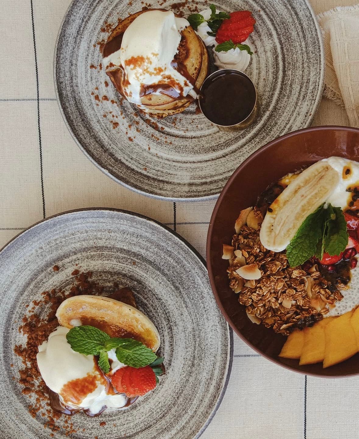 Pancakes with cream and a granola bowl with mango