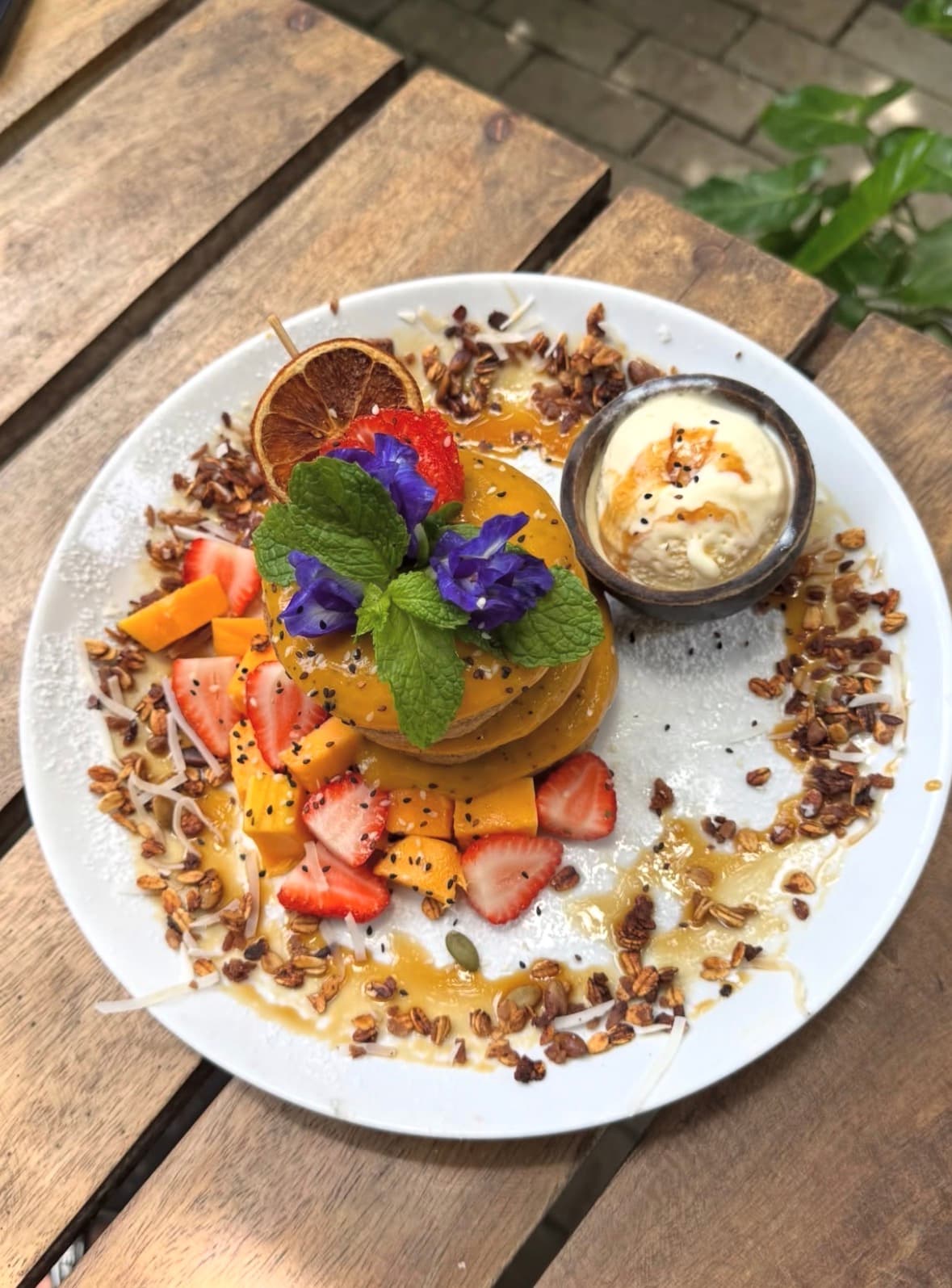 Stacked pancakes with mango, strawberries and ice cream